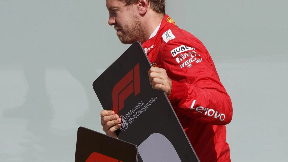 Sebastian Vettel sposta il tabellone che indica il primo posto (foto Ansa)