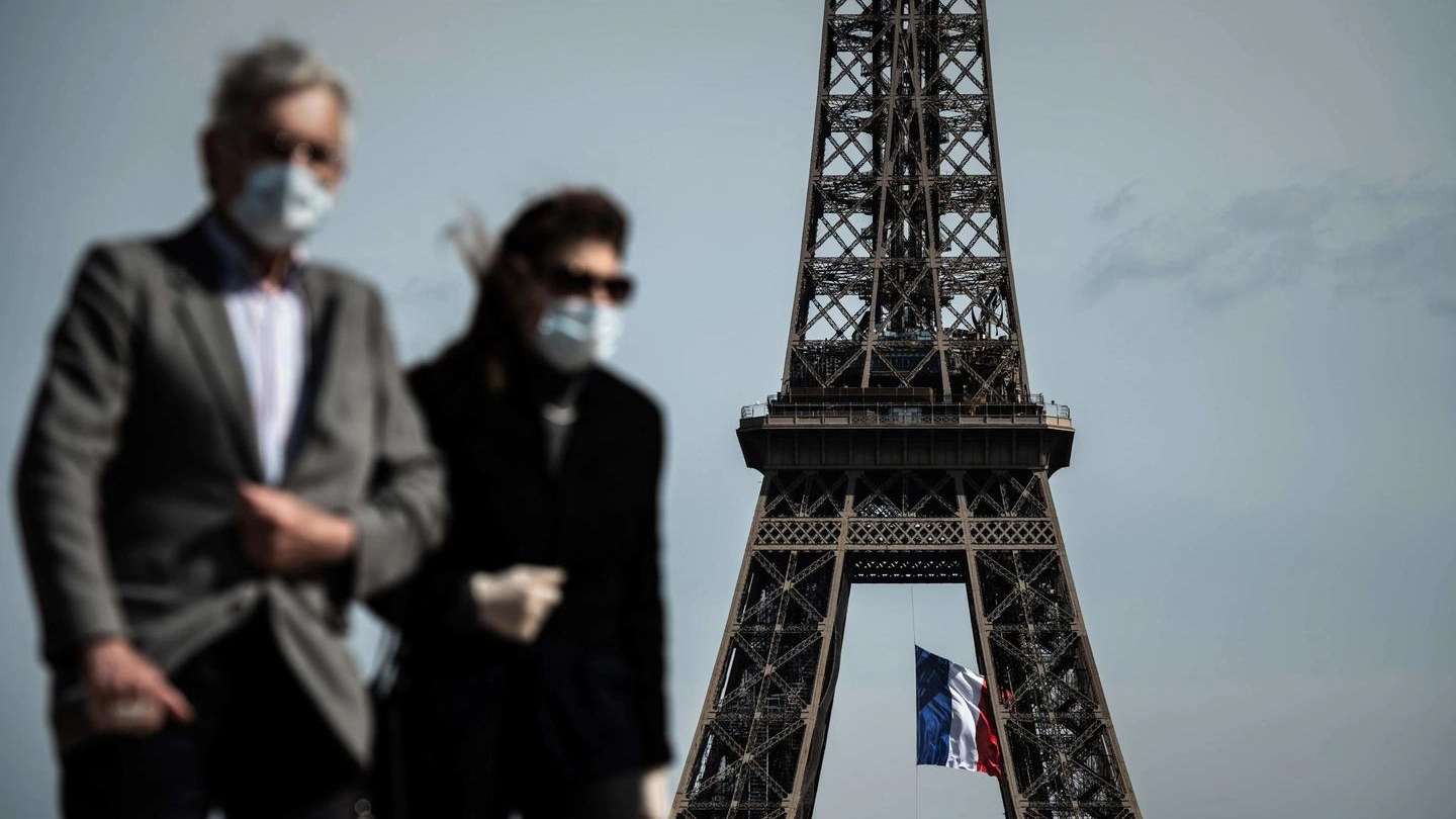 Coronavirus, persone con la mascherina vicino alla Tour Eiffel (Ansa)