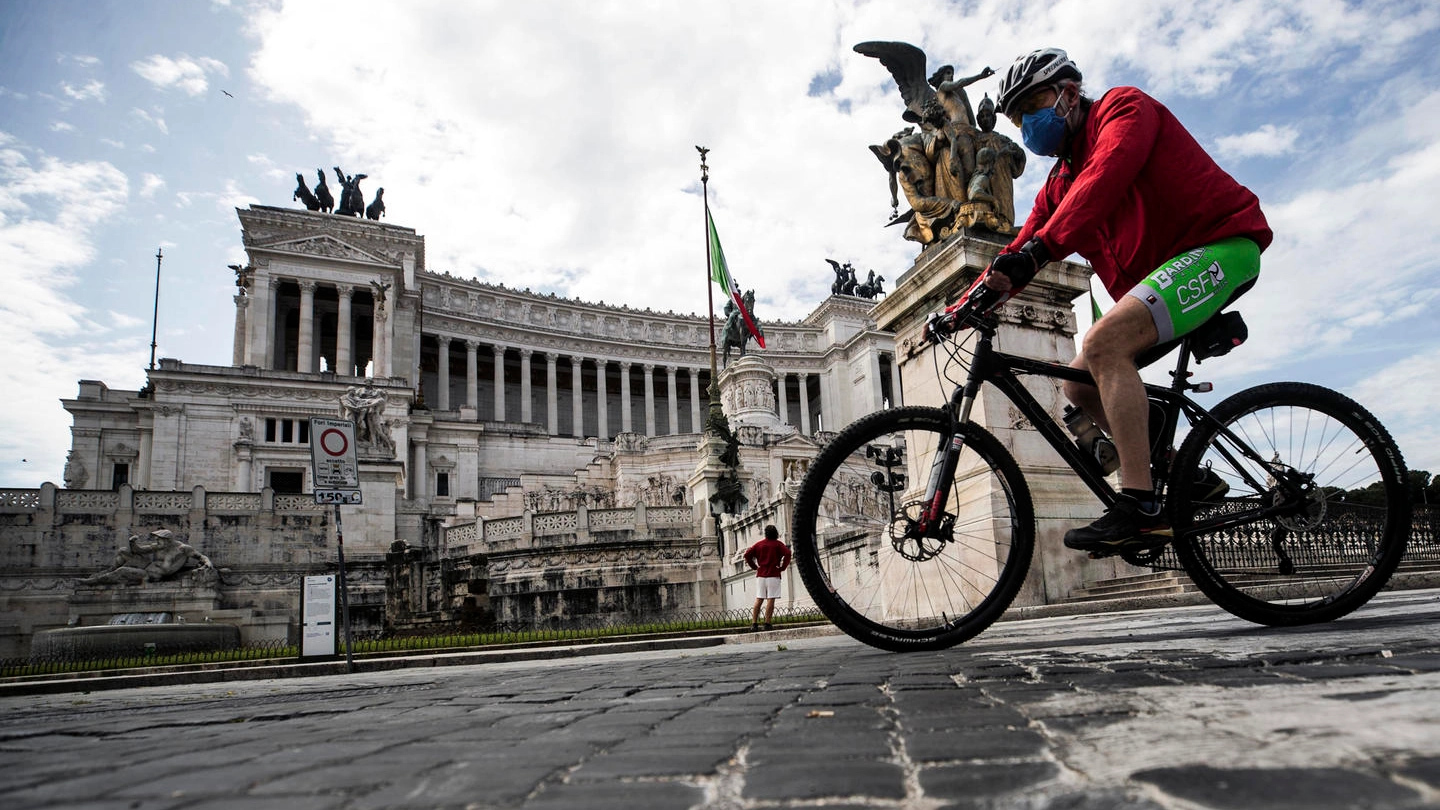 Un ciclista con la mascherina per le vie di Roma (Ansa)