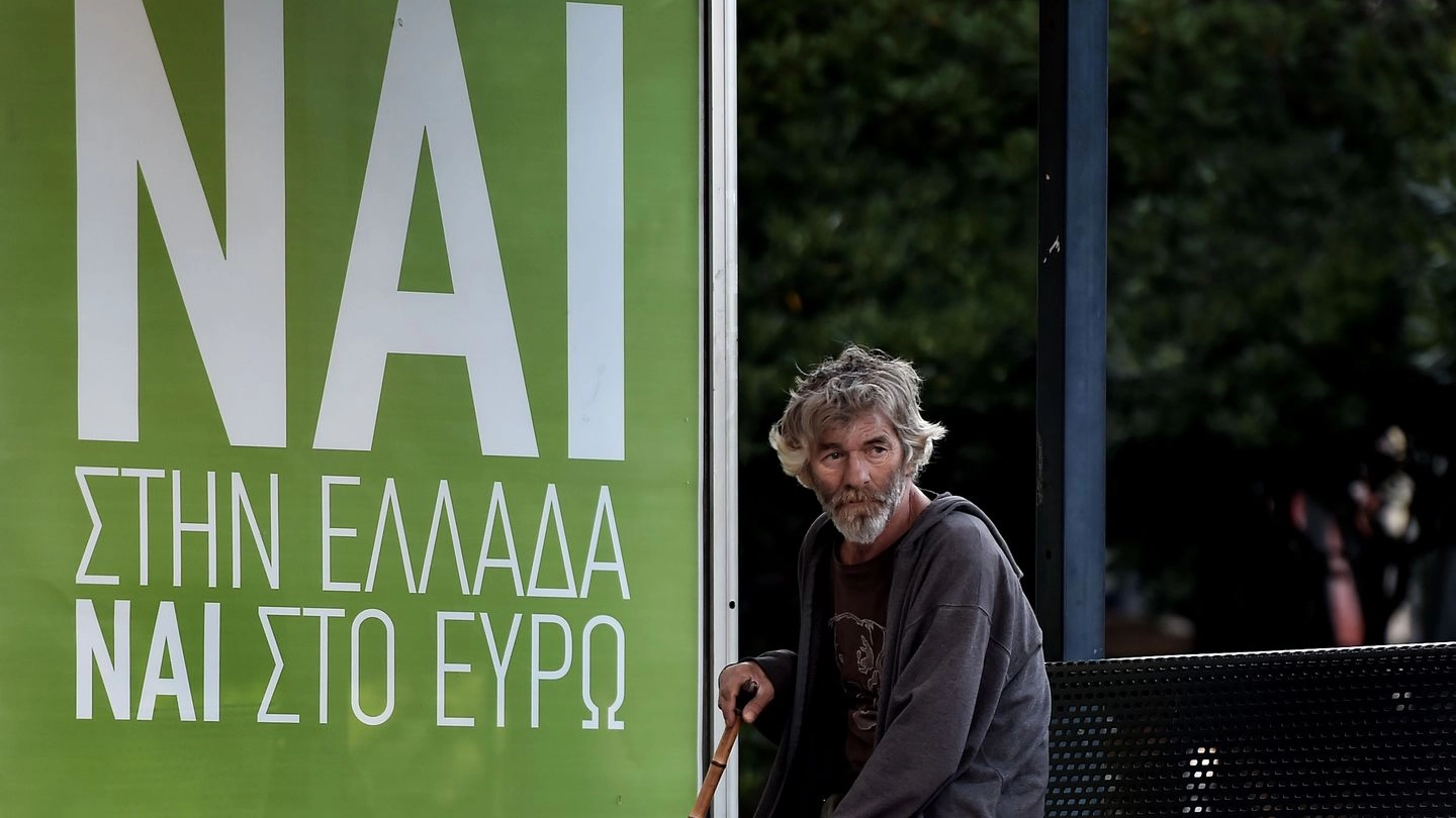 Un anziano accanto a un cartello: "Sì alla Grecia, sì all'euro" (Afp)