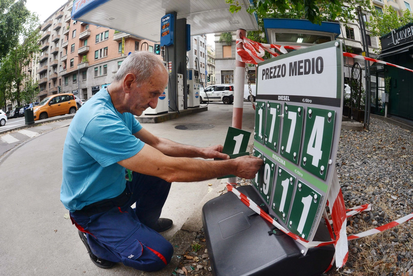 Un benzinaio aggiorna la cartellonistica che indica i prezzi medi regionali di benzina e gasolio