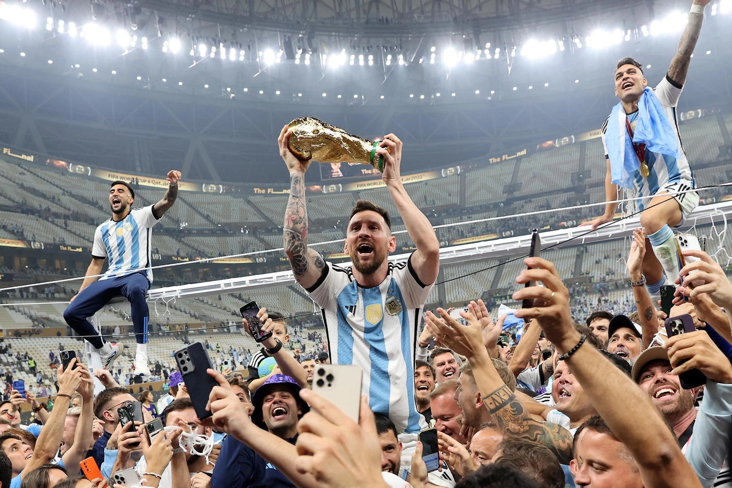 Messi con la Coppa del Mondo insieme a tifosi e compagni dell'Argentina (Ansa)