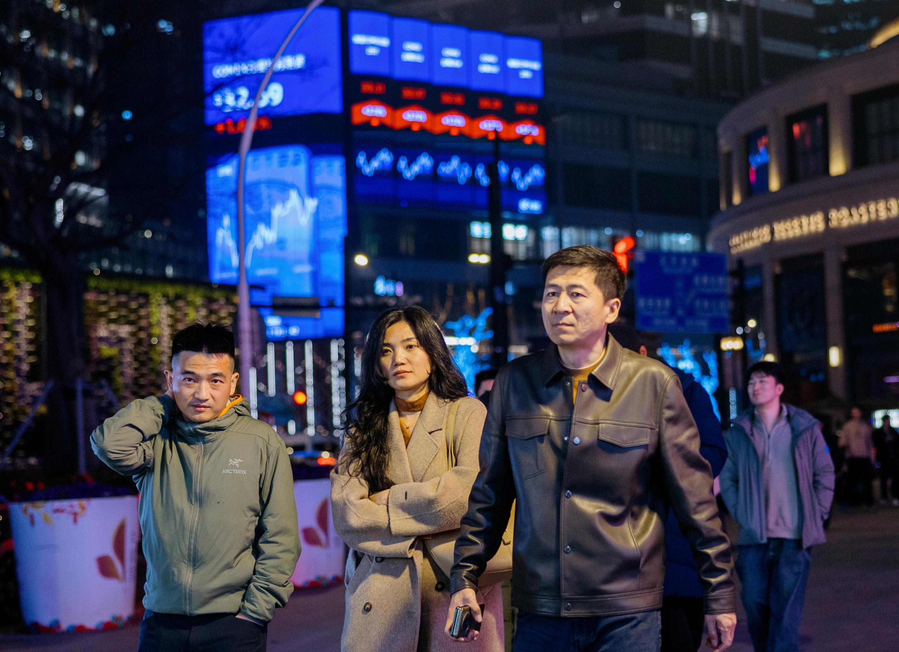 Shanghai, gente cammina davanti a un megaschermo con le ultime notizie di Borsa (Ansa)