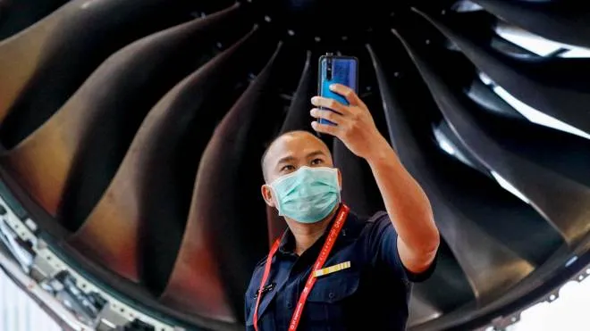 epa08210292 A man wearing a protective mask poses for a photo next to a mock up Rolls Royce Trent XWB turbofan engine during the Singapore Airshow at the Changi Exhibition Centre in Singapore, 11 February 2020. Lockheed Martin, as well as other manufacturers like Embraer, Bombardier and COMAC, have announced their withdrawal from the Singapore Airshow in light of the outbreak of the novel coronavirus (2019-nCoV) on the city-state. The Singapore Airshow runs from 11 to 16 February 2020 showcasing aviation and defense technologies from around the world.  EPA/WALLACE WOON