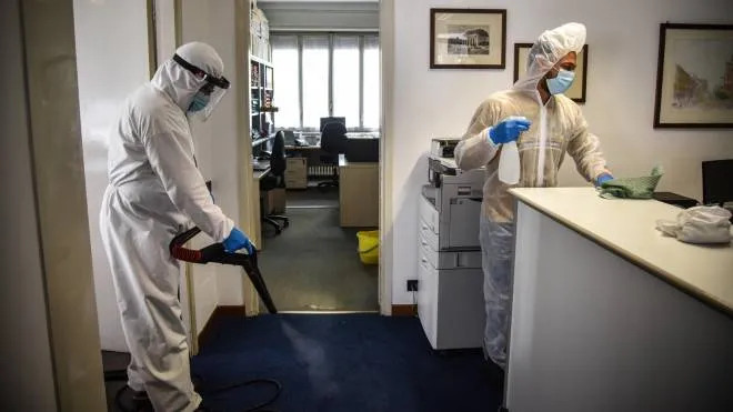 Sanification workers, in white overalls, spray disinfectant stops and clean an office ahead of reopening after the Covid-19 emergency lockdown, Milan, Italy, 02 May 2020.  ANSA / Matteo Corner