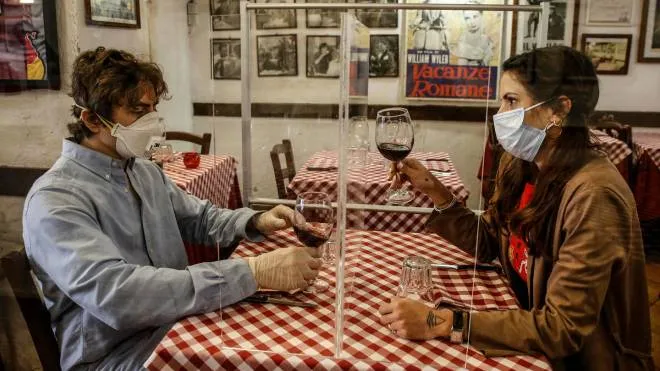 Valerio Calderoni, owner of a italian tipical restaurant, and his wife Martina, pose for a picture during a test for a of possible plexiglass separator between tables of restaurant ''Il Ciak'', Trastevere district in Rome, Italy, 23 April 2020. Countries around the world are taking measures to stem the widespread of the SARS-CoV-2 coronavirus which causes the Covid-19 disease. ANSA / FABIO FRUSTACI