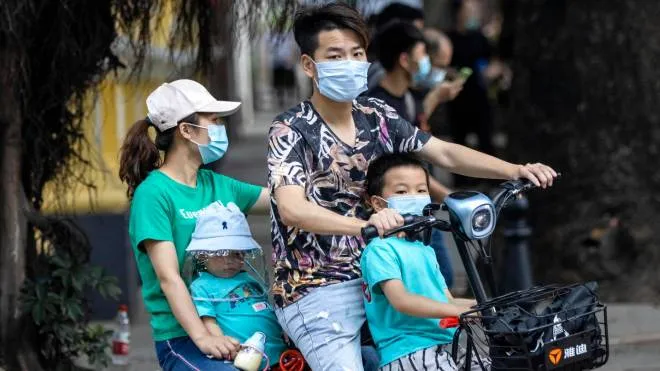 epa08395479 A family wearing masks ride on the motorcycle in Guangzhou, Guangdong province, China, 1 May 2020. China is loosening up nationwide restrictions after months of lockdown over the coronavirus crisis. Labor Day in the country kicked off with a long weekend and an extended holiday, from 01 to 05 May, after the tourism industry has been hit during the coronavirus disease (COVID-19) pandemic.  EPA/ALEX PLAVEVSKI