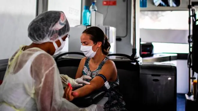 A nurse prepares to take a blood sample from a woman for a coronavirus test inside a bus converted into a test lab at the Sao Domingos de Rana high school in Cascais on September 14, 2020. - A coronavirus bus travelled through several schools in Cascais in the outskirts of Lisbon to deliver free COVID-19 tests to teachers and school employees days before the beginning of the academic year. (Photo by PATRICIA DE MELO MOREIRA / AFP)