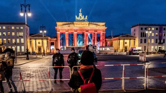 epa08911535 A visitor near the Brandenburg Gate in the Pariser Platz in Berlin, Germany, 30 December 2020. This year's event will take place as a television production without an audience due to the coronavirus pandemic.  EPA/FILIP SINGER