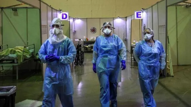 TOPSHOT - Healthcare workers wearing protective gear prepare to attend  patients at the Portimao Arena sports pavilion converted in a field hospital for Covid-19 patients at Portimao, in the Algarve region, on February 9, 2021. (Photo by PATRICIA DE MELO MOREIRA / AFP)