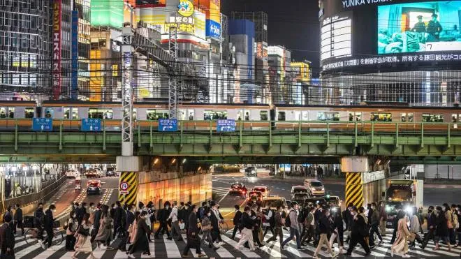 Pedestrians cross a street at night in Tokyo's Shinjuku area on April 2, 2021 as the city reported 440 new infections of the Covid-19 coronavirus. (Photo by CHARLY TRIBALLEAU / AFP)