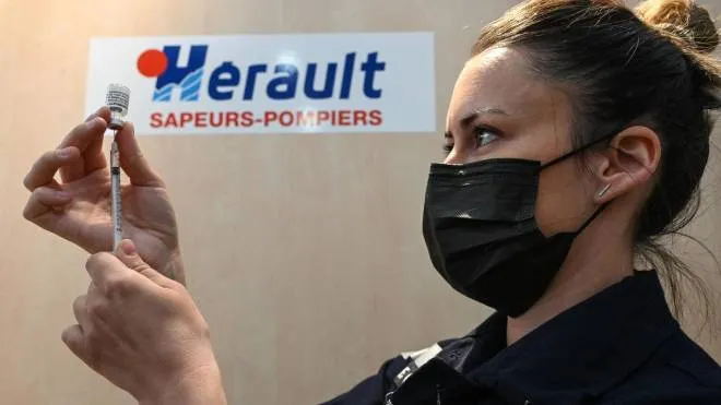 A woman firefighter prepares doses of the Pfizer-BioNTech vaccine against Covid-19, at the SDIS34 fire station transformed into a temporary vaccination center, in Vailhauques near Montpellier in the south of France, April 8, 2021, during a vaccination campaign aimed at curbing the spread of the Covid-19 pandemic. (Photo by Pascal GUYOT / AFP)