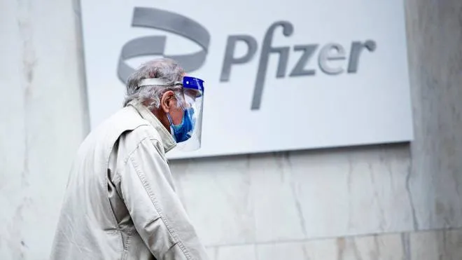 (FILES) In this file photo a man wearing facemask and shield walks past the Pfizer headquarters in New York on March 11, 2021, one year after the pandemic was officially declared. - Pfizer sharply increased its projections for 2021 revenues and profits on May 4, 2021, citing much higher sales from its Covid-19 vaccine sales.The drugmaker now estimates 2021 revenues of $26 billion from the vaccine, up from $15 billion previously and reflecting 1.6 billion doses expected to be delivered this year under contracts signed through mid-April. (Photo by Kena Betancur / AFP)