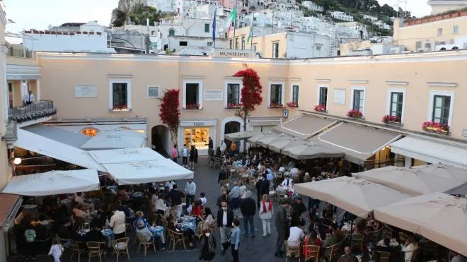 Tourists stroll and have a coffee at the bar in the 'Piazzetta' square on the island of Capri (Naples), 23 May 2021. Tourists return to Capri after the Covid-19 pandemic. The island of Capri, recently declared Covid free having completed the mass vaccination, begins to repopulate. ANSA/ GIUSEPPE CATUOGNO