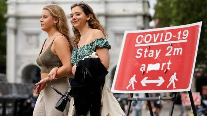Pedestrians walk past a sign asking people to social distance, near Marble Arch in central London on June 6, 2021. - The Delta variant of the coronavirus, first discovered in India, is estimated to be 40 percent more transmissible than the Alpha variant that caused the last wave of infections in the UK, Britain's health minister said Sunday. (Photo by Tolga Akmen / AFP)