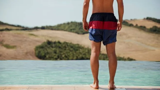 One young man standing by the swimming pool at a holiday villa in Tuscany, Italy.