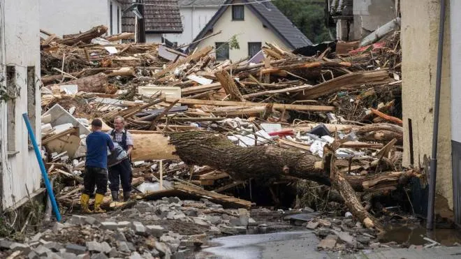 TOPSHOT - Two men remove try to secure goods from next to debris of houses destroyed by the floods in Schuld near Bad Neuenahr, western Germany, on July 15, 2021. - Heavy rains and floods lashing western Europe have killed at least 42 people in Germany and left many more missing, as rising waters led several houses to collapse. (Photo by Bernd Lauter / AFP)
