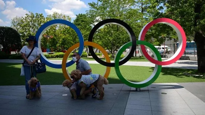 Visitors pose for pictures with their dogs in front of the Olympic Rings at the Japan Olympic museum outside the National Stadium, main venue of the Tokyo 2020 Olympic Games in Tokyo on July 19, 2021. (Photo by Philip FONG / AFP)