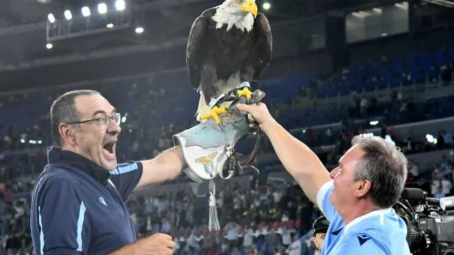 Lazio's Italian coach Maurizio Sarri (L) celebrates with Lazio's eagle mascotte Olimpia at the end the Italian Serie A football match Lazio vs AS Roma at the Olympic stadium in Rome on September 26, 2021. (Photo by Vincenzo PINTO / AFP)