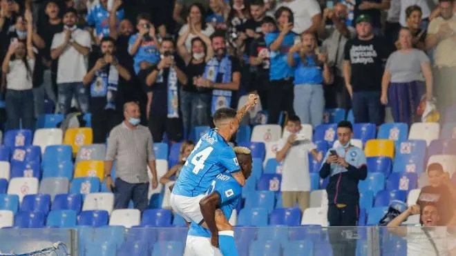 Napoli's Nigerian forward Victor Osimhen carries Napoli's Italian forward Lorenzo Insigne as they celebrate with fans after Osimhen opened the scoring during the Italian Serie A between Napoli and Cagliari on September 26, 2021 at the Diego-Maradona stadium in Naples. (Photo by Carlo Hermann / AFP)