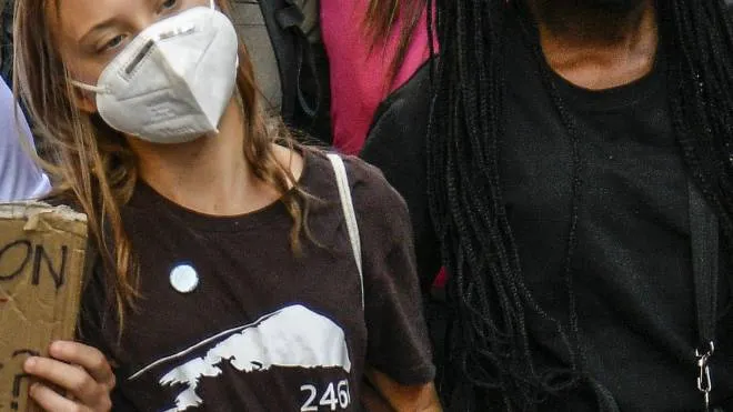 Alcuni manifesti, a Milano, con il mondo che soffre. A sinistra, le attiviste Greta Thunberg, svedese di 18 anni, e Vanessa Nakate, ugandese di 24 anni