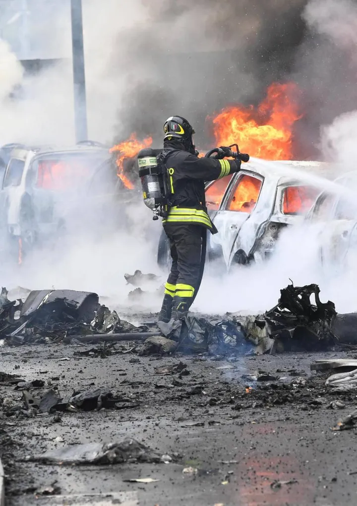 Le auto incendiate dopo l’impatto. In alto, la colonna di fumo nel cielo di Milano