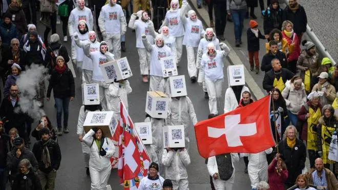 Protesters hold flags and banners during a protest against the current measures to tackle the spread of the coronavirus, Covid-19 health pass and vaccination, in Lausanne on November 20, 2021. - On November 28, 2021, Swiss will vote on challenging the law underpinning many of the government�s coronavirus measures. The country�s vaccination rate is lower than that of many other European nations. (Photo by Fabrice COFFRINI / AFP)