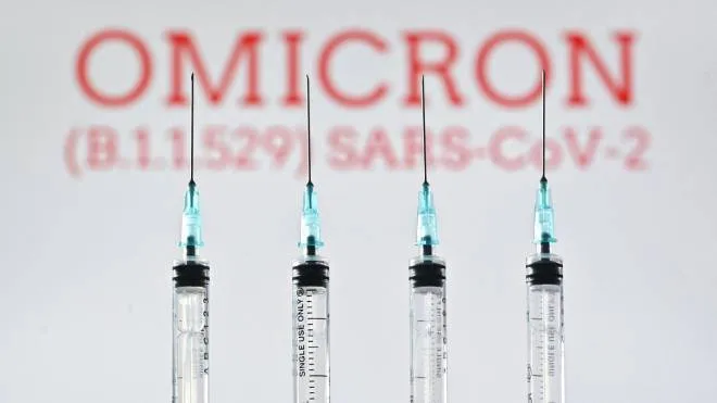 An illustration picture taken in London on December 2, 2021 shows four syringes and a screen displaying the word 'Omicron',  the name of the new covid 19 variant. (Photo by Justin TALLIS / AFP)