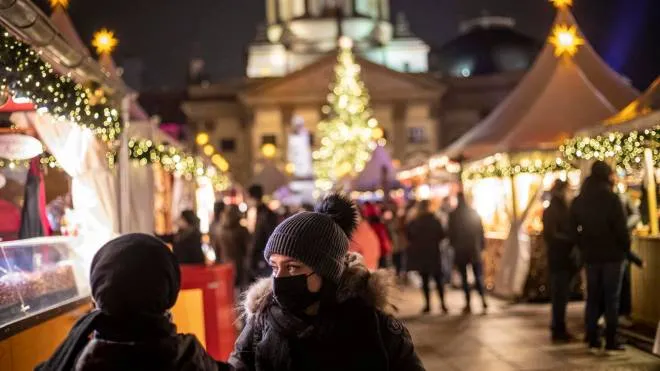 epa09627924 People wearing protective face masks walk at a Christmas market at Gendarmenmarkt square, in Berlin, Germany, 07 December 2021. Germany is dealing with a rising number of new coronavirus COVID-19 infections as countries throughout Europe have been increasing restrictions amid fear of the new Omicron variant of concern.  EPA/MARTIN DIVISEK
