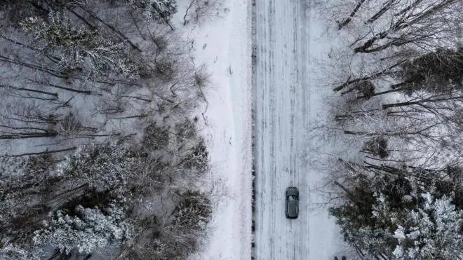 This photograph taken on December 9, 2021, shows an aerial view of a car driving on snow road in  Xonrupt-Longemer, eastern France. (Photo by SEBASTIEN BOZON / AFP)
