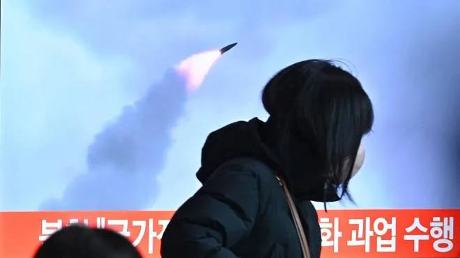 People walk past a television screen showing a news broadcast with file footage of a North Korean missile test, at a railway station in Seoul on January 11, 2022, after North Korea fired a "suspected ballistic missile" into the sea, South Korea's military said, less than a week after Pyongyang reported testing a hypersonic missile. (Photo by Anthony WALLACE / AFP)