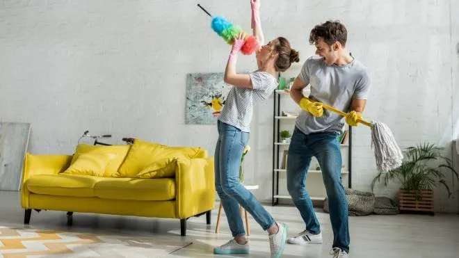 man and woman with household singing while doing spring cleaning in living room