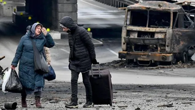 Alcuni civili in fuga con i loro bagagli tra le macerie di Kiev. Più di un milione e 200mila persone hanno lasciato il Paese