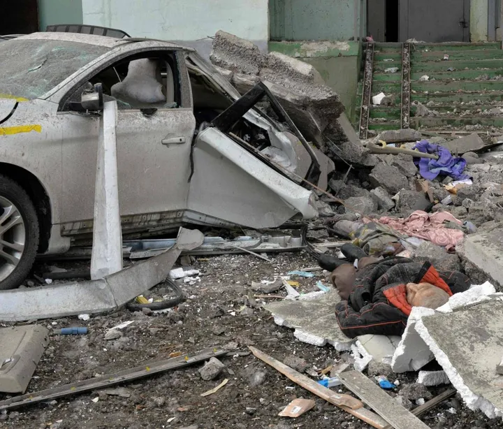 Il corpo senza vita di un uomo giace accanto a una macchia distrutta dopo l’ennesimo bombardamento a Kharkiv