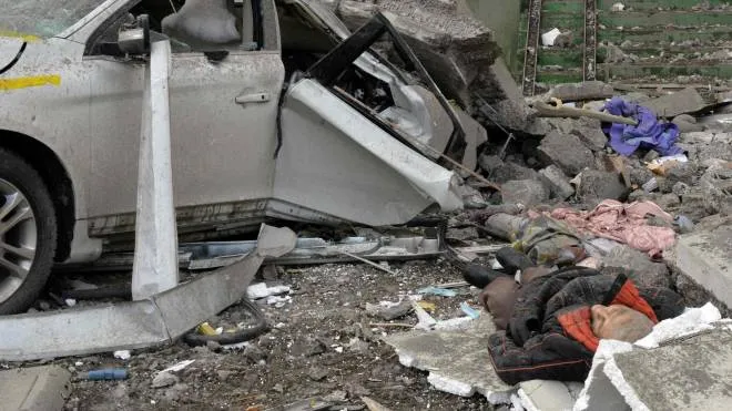 Il corpo senza vita di un uomo giace accanto a una macchia distrutta dopo l’ennesimo bombardamento a Kharkiv