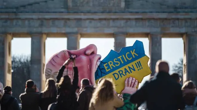 Un carro di carnevale alla Porta di Brandeburgo a Berlino mostra Putin che ingoia un oggetto con i colori e la forma dell’Ucraina