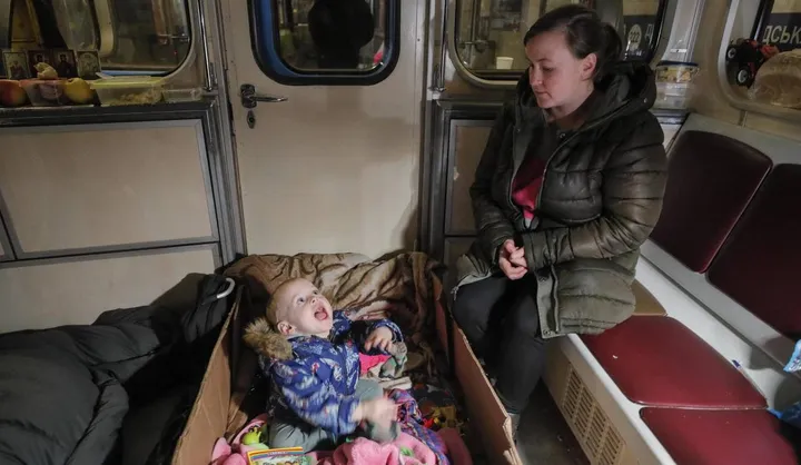 Mamma e figlia al riparo in un vagone della metropolitana a Kiev. La bimba gioca e dorme in una scatola di cartone