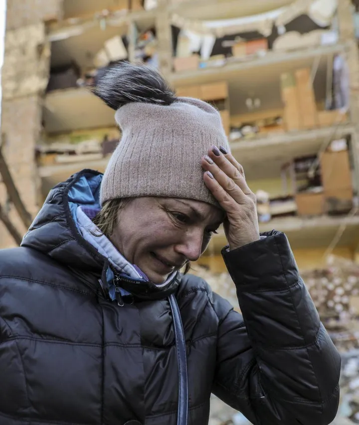 Una donna piange davanti a un palazzo di Kiev centrato dai missili delle forze armate del Cremlino
