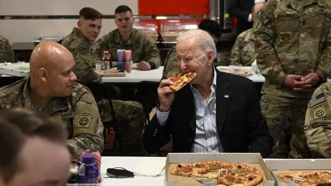 US President Joe Biden (C) eats a pizza as he meets with service members from the 82nd Airborne Division, who are contributing alongside Polish Allies to deterrence on the Alliance�s Eastern Flank, in the city of Rzeszow in southeastern Poland, around 100 kilometres (62 miles) from the border with Ukraine, on March 25, 2022. (Photo by Brendan SMIALOWSKI / AFP)