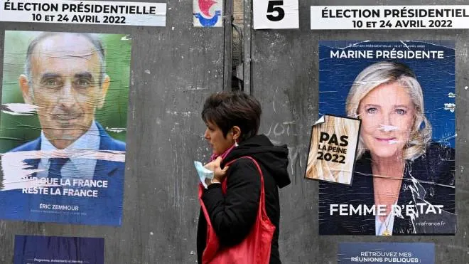 Parigi, una donna passa davanti ai manifesti di Éric Zemmour e Marine Le Pen alla vigilia del voto di domani