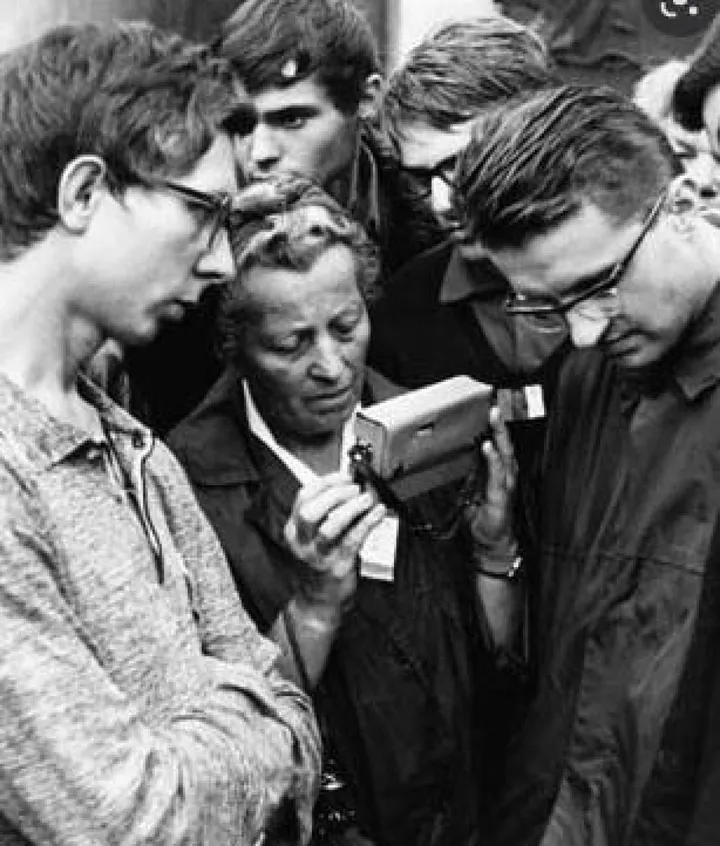 Praga 1968: gruppo d’ascolto attorno a una radiolina durante l’effimera “primavera“