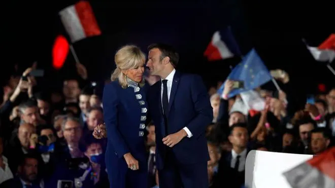 epa09907437 French President Emmanuel Macron and his wife Brigitte Macron celebrate on stage after winning the second round of the French presidential elections at the Champs-de-Mars after Emmanuel Macron won the second round of the French presidential elections in Paris, France, 24 April 2022. Emmanuel Macron defeated Marine Le Pen in the final round of France's presidential election, with exit polls indicating that Macron is leading with approximately 58 percent of the vote.  EPA/GUILLAUME HORCAJUELO