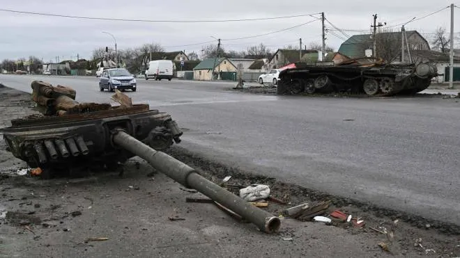 Cars ride by the wreckage of a tank on a road northeast of Kyiv on April 19, 2022, amid Russian invasion of Ukraine. (Photo by Genya SAVILOV / AFP)