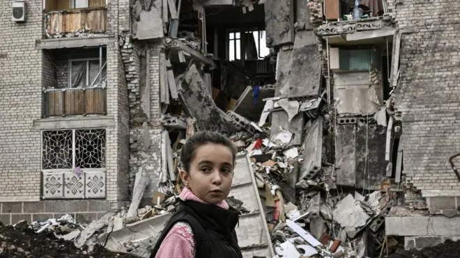 Una bambina davanti al palazzo distrutto dove abitava a Bakhmut, nel Donbass