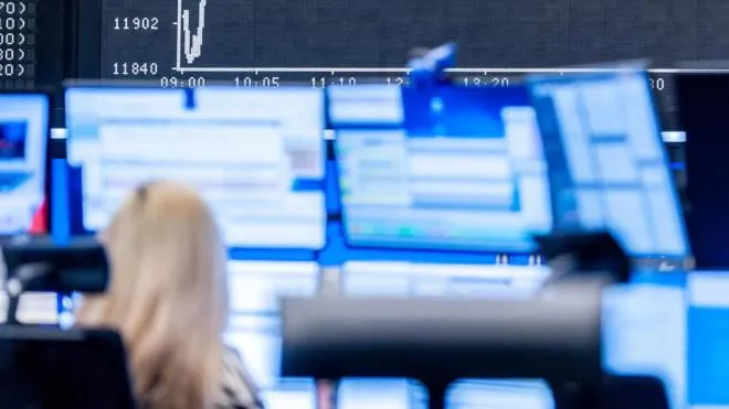 epa08797900 An electronic display shows the DAX chart, as a trader works in front of her computer screens at the trading floor of the Deutsche Boerse stock exchange, the morning following the US Presidential Election, in Frankfurt/Main, Germany, 04 November 2020. The German stock index DAX opened weakly but rebounded quickly despite inconclusive news about the outcome of the US elections.  EPA/MAXIMILIAN VON LACHNER