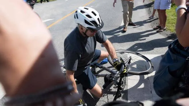 US President Joe Biden falls off his bicycle as he approaches well-wishers following a bike ride at Gordon's Pond State Park in Rehoboth Beach, Delaware, on June 18, 2022. (Photo by SAUL LOEB / AFP)