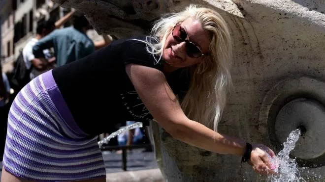 Una turista si rinfresca in questi giorni roventi nella fontana della Barcaccia, in piazza di Spagna, a Roma