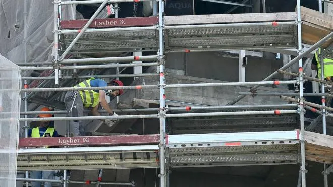 Operai edili al lavoro sulla facciata di  un palazzo ricoperto da ponteggi, Milano, 14 giugno 2022. ANSA/DANIEL DAL ZENNARO