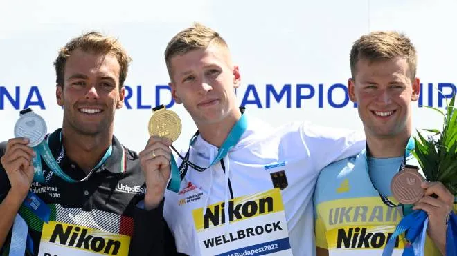 epa10036182 (L-R) Silver medalist Gregorio Paltrinieri of Italy, gold medalist Florian Wellbrock of Germany and bronze medalist Mykhailo Romanchuk of Ukraine pose for photographs during the award ceremony for the men's 5km open water swimming of the 19th FINA World Championships at Lupa lake near Budapest, Hungary, 27 June 2022.  EPA/Zsolt Szigetvary HUNGARY OUT