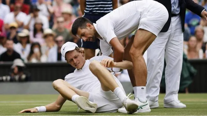 epa10053575 Jannik Sinner (L) of Italy is helped by his opponent Novak Djokovic of Serbia after falling on court in their men's quarter final match at the Wimbledon Championships, in Wimbledon, Britain, 05 July 2022.  EPA/TOLGA AKMEN   EDITORIAL USE ONLY